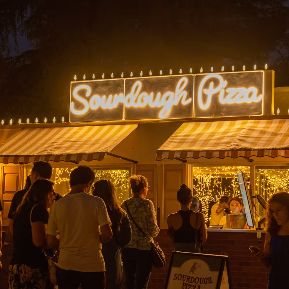 Guests lining up at the glowing Sourdough Pizza stand
